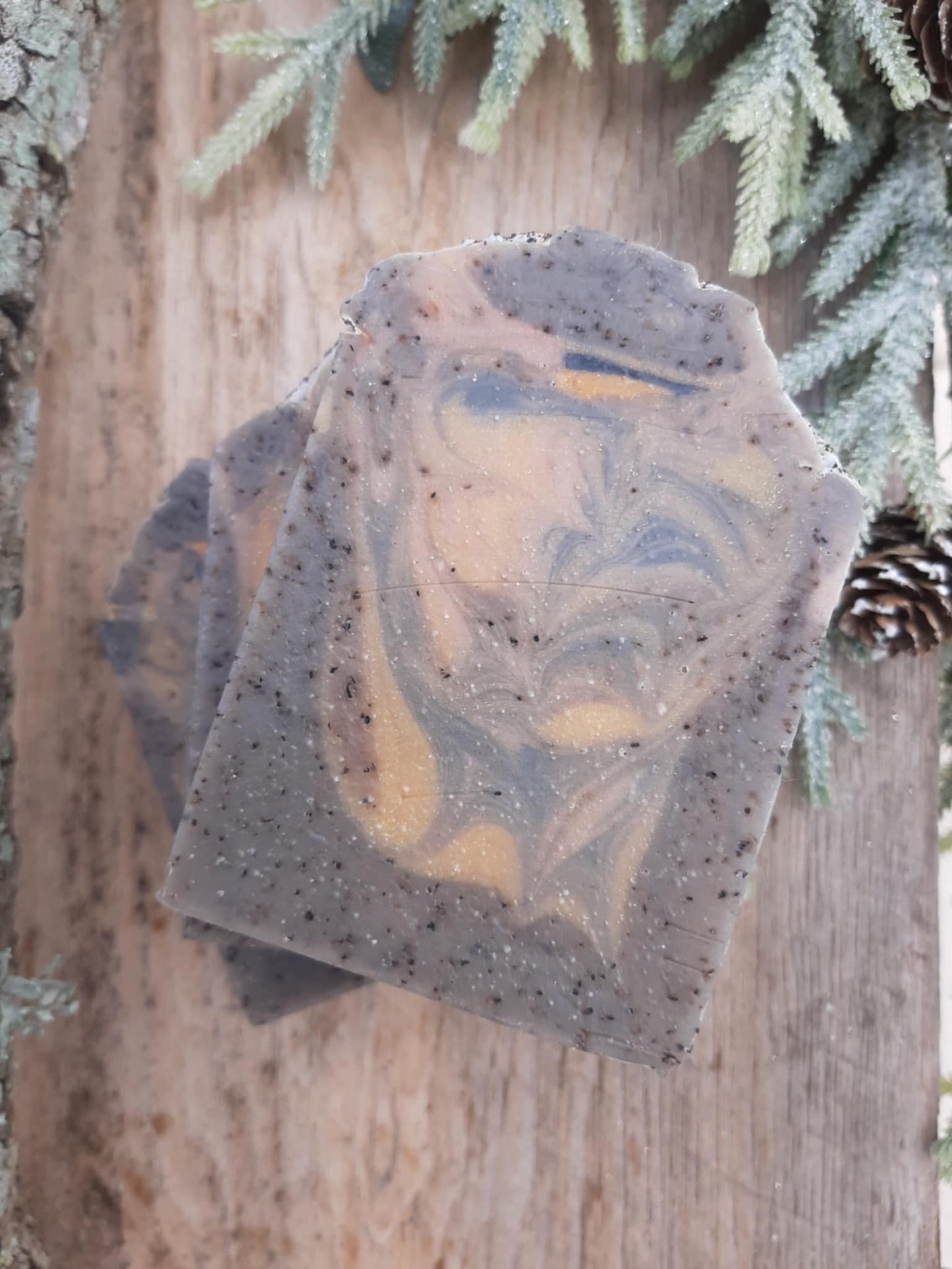 Handmade organic cedar and amber black tea body bar with embedded tea leaves and wood chips, rich amber hue, rustic soap on cedar plank