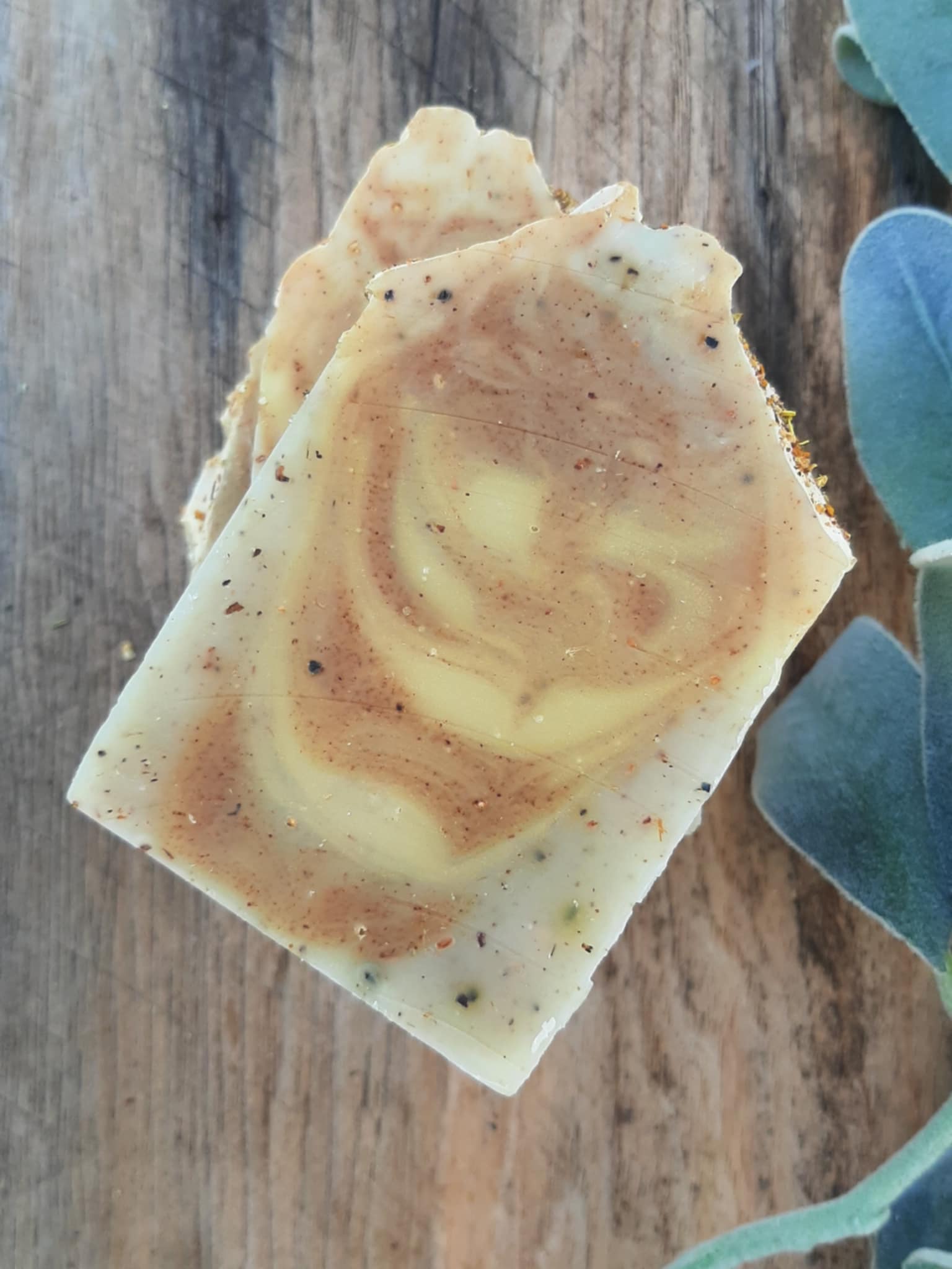 Handmade organic ginger turmeric aloe body bar with orange peel flecks and turmeric swirl, golden glow on bamboo soap dish, spa wellness vibe