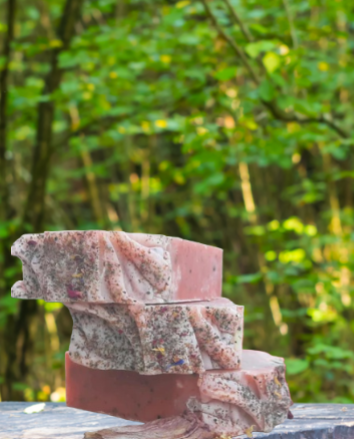 Handmade organic hibiscus tea aloe and nectar body bar with dried hibiscus petals and aloe flecks, vibrant pink swirl, on marble with fresh flowers