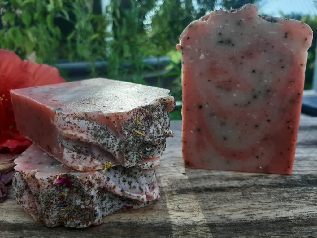 Handmade organic hibiscus tea aloe and nectar body bar with dried hibiscus petals and aloe flecks, vibrant pink swirl, on marble with fresh flowers